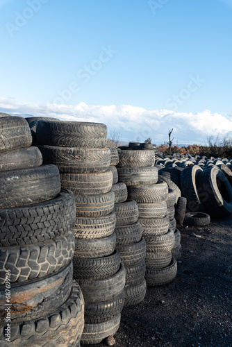 Used tire dump, rubber waste and recycling challenges. Tires of various sizes and brands are piled up in irregular stacks, disturbing landscape of industrial waste