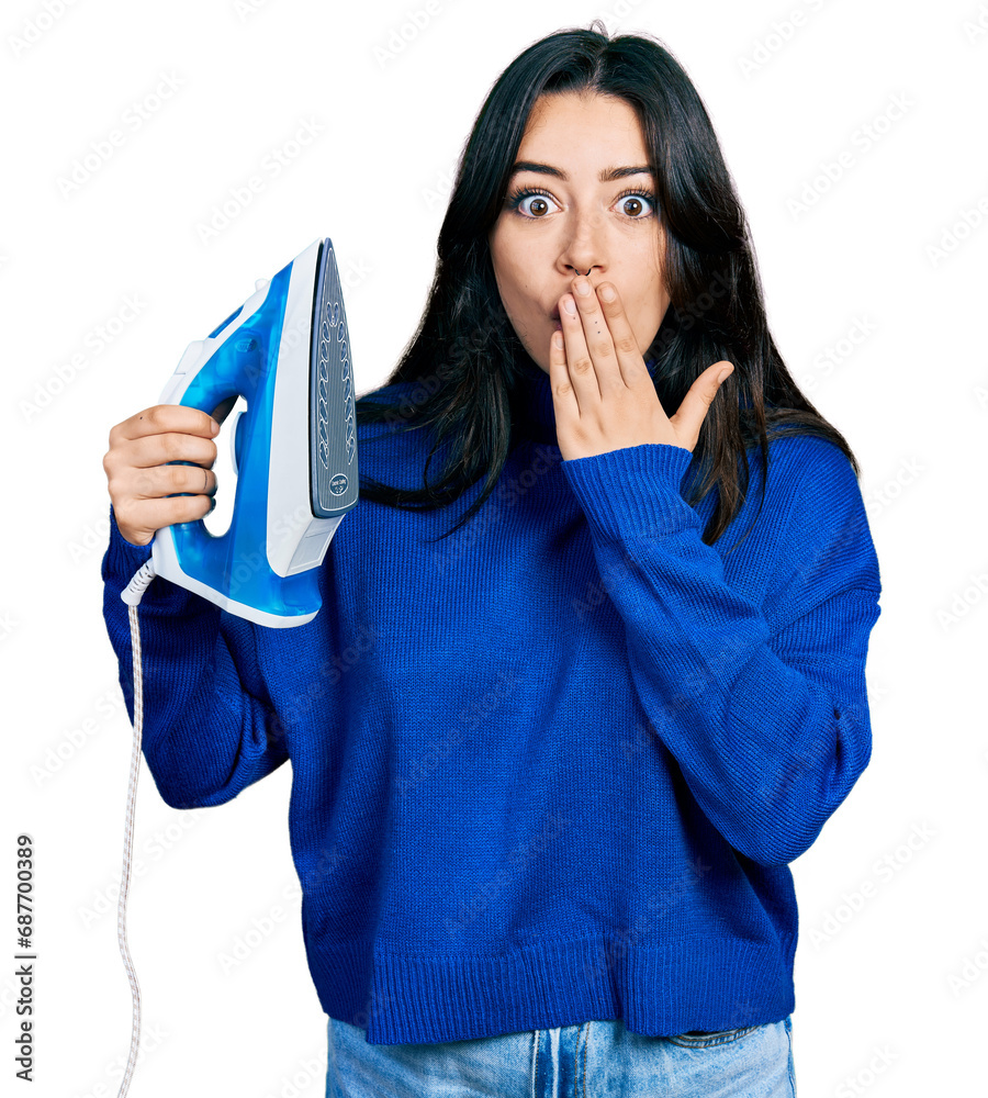 Beautiful hispanic woman holding electric steam iron covering mouth with hand, shocked and afraid for mistake. surprised expression Beautiful hispanic woman holding electric steam iron covering mouth with hand, shocked and afraid for mistake. surprised expression