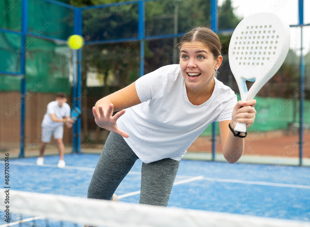European young woman tennis player playing padel during friendly match on outdoor court in spring