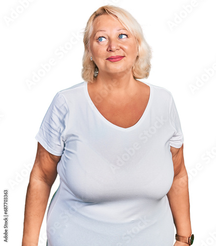 Middle age blonde woman wearing casual white t shirt smiling looking to the side and staring away thinking.