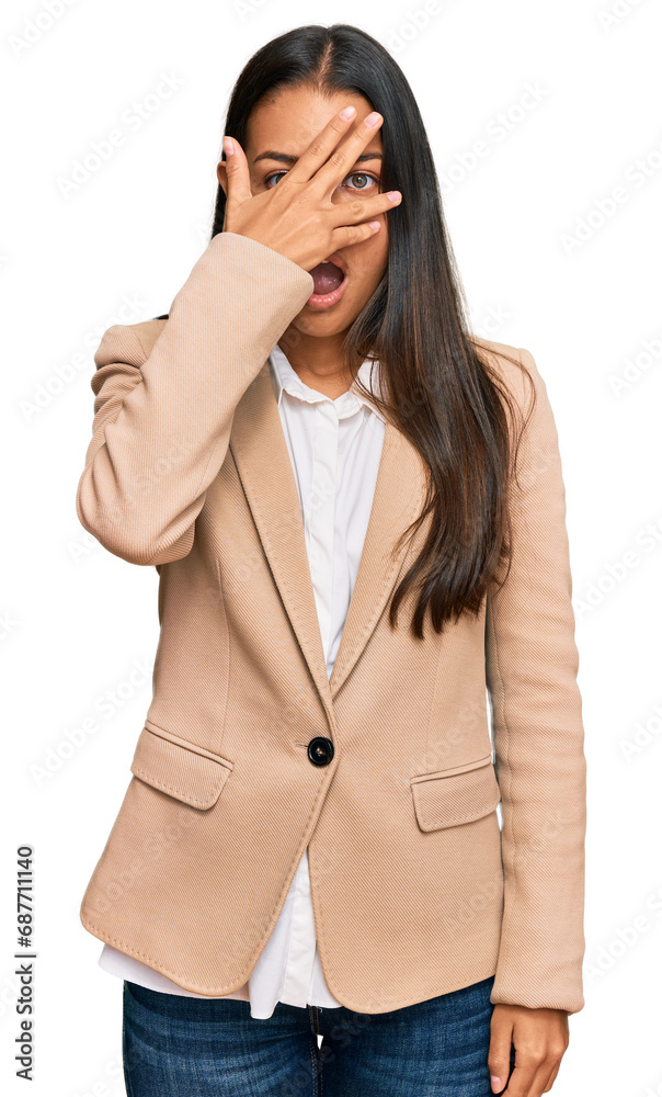 Beautiful hispanic woman wearing business jacket peeking in shock covering face and eyes with hand, looking through fingers with embarrassed expression. Beautiful hispanic woman wearing business jacket peeking in shock covering face and eyes with hand, looking through fingers with embarrassed expression.