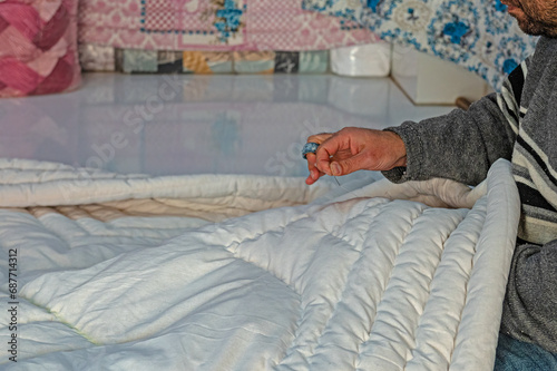 Man sewing quilts in his shop using traditional methods. photo