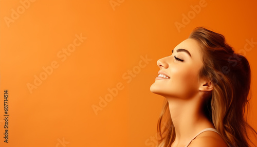 Mujer joven con cabello castaño sonriendo sobre fondo naranja. Espacio para texto.