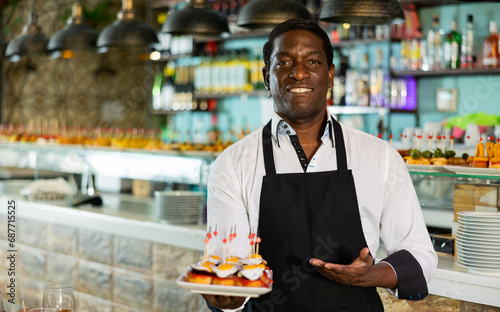 Professional friendly african american waiter holding serving tray for restaurant guests