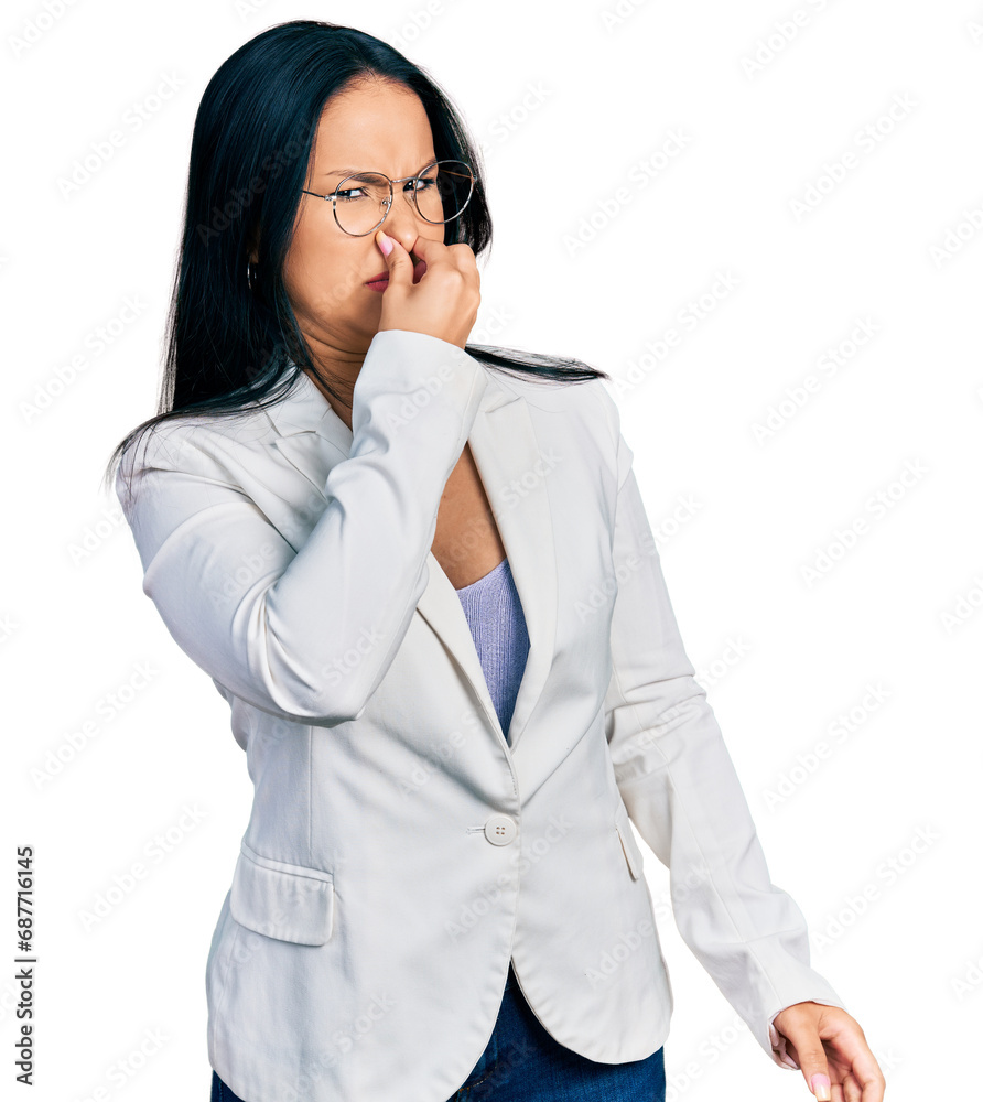 Beautiful hispanic woman with nose piercing wearing business jacket and glasses smelling something stinky and disgusting, intolerable smell, holding breath with fingers on nose. bad smell Beautiful hispanic woman with nose piercing wearing business jacket and glasses smelling something stinky and disgusting, intolerable smell, holding breath with fingers on nose. bad smell