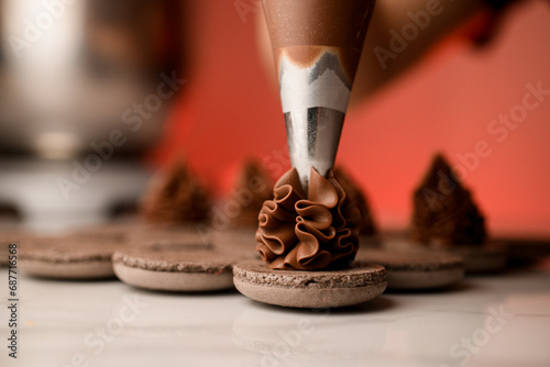 Cuadro en lienzo Female hands of a confectioner squeeze chocolate cream onto halves of chocolate