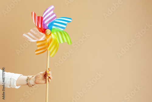 Stylish woman in blouse and shorts with windmill toy on beige