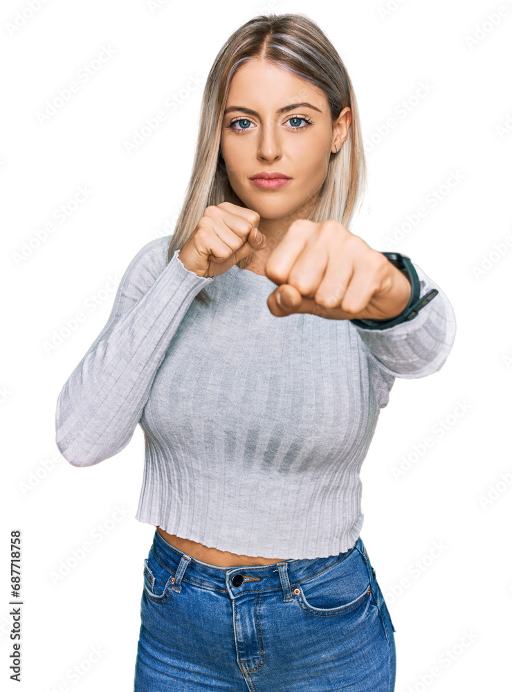 Beautiful blonde woman wearing casual clothes punching fist to fight, aggressive and angry attack, threat and violence Beautiful blonde woman wearing casual clothes punching fist to fight, aggressive and angry attack, threat and violence