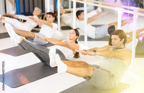 Group of sports people doing pilates on yoga mats