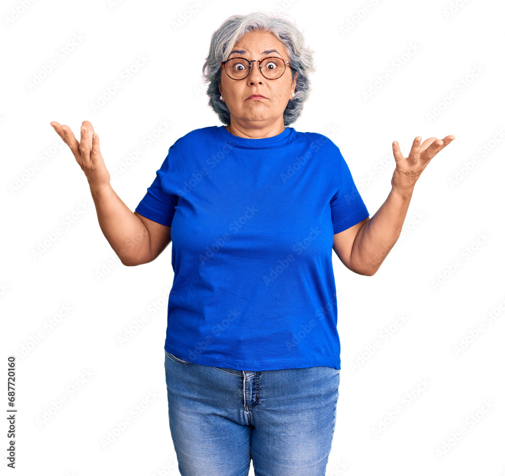 Senior woman with gray hair wearing casual clothes and glasses clueless and confused expression with arms and hands raised. doubt concept. Senior woman with gray hair wearing casual clothes and glasses clueless and confused expression with arms and hands raised. doubt concept.