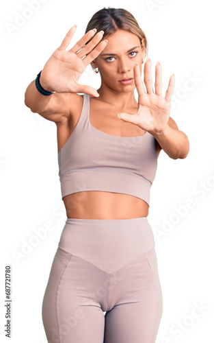 Beautiful caucasian woman wearing sportswear doing frame using hands palms and fingers, camera perspective