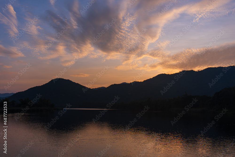 Beautiful lakeside view from a small lake in Kanchanaburi Thailand, with water reflect sunset sky.