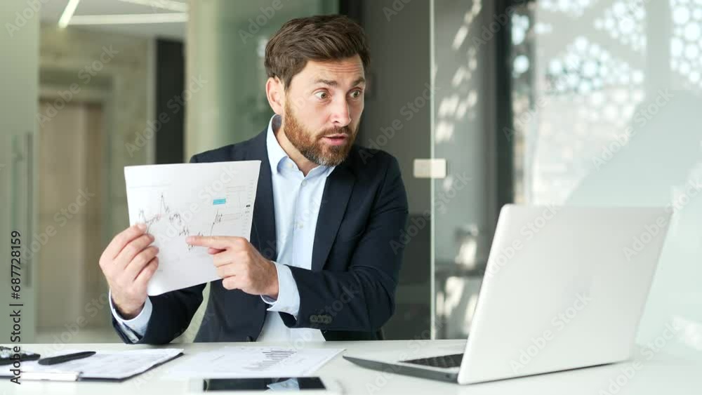 Angry businessman boss in formal suit arguing over a video call using a laptop sitting at a workplace in office. Unsatisfied manager shows a diagram and tells subordinates about the company's problems Angry businessman boss in formal suit arguing over a video call using a laptop sitting at a workplace in office. Unsatisfied manager shows a diagram and tells subordinates about the company's problems
