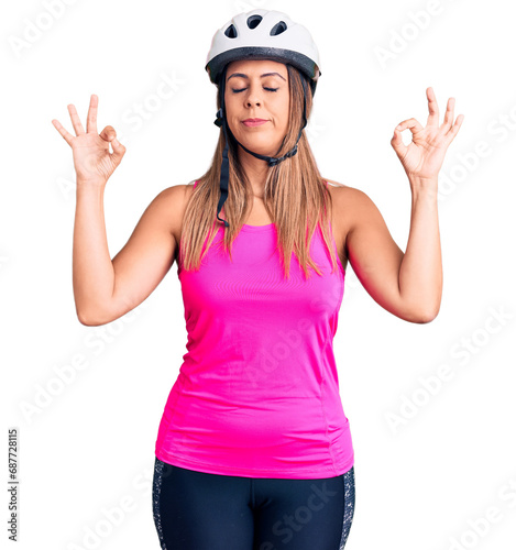Young beautiful woman wearing bike helmet relax and smiling with eyes closed doing meditation gesture with fingers. yoga concept. © Krakenimages.com