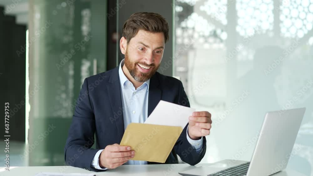 Happy excited businessman in formal suit reading letter with great news sitting at desk at workplace in business office. Worker is celebrating success, happy to receive a pleasant notification. Wow Happy excited businessman in formal suit reading letter with great news sitting at desk at workplace in business office. Worker is celebrating success, happy to receive a pleasant notification. Wow