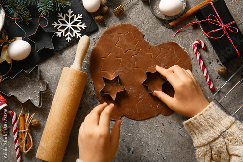 Woman preparing tasty Christmas gingerbread cookies on grunge grey background