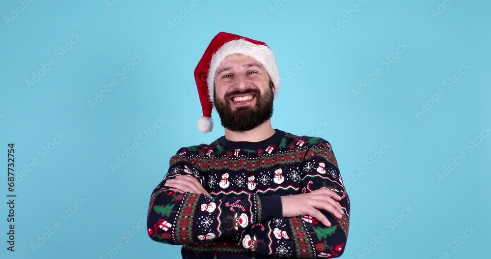 Young bearded man in christmas sweater and santa hat smiling on blue isolated background, male in new year clothes looking at camera. Young bearded man in christmas sweater and santa hat smiling on blue isolated background, male in new year clothes looking at camera.