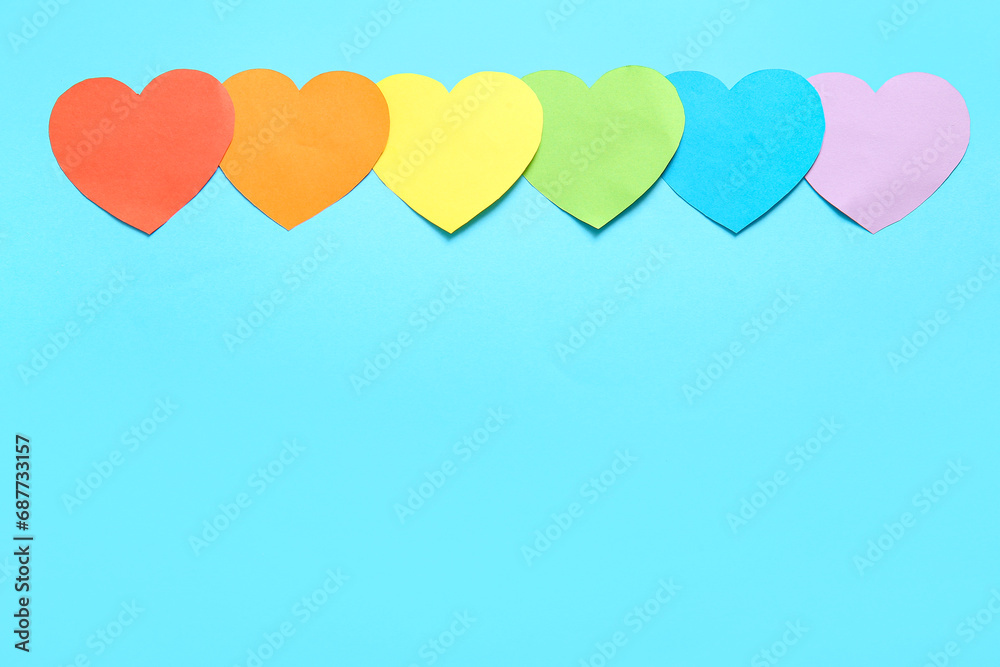 Colorful paper hearts on blue background. LGBT concept