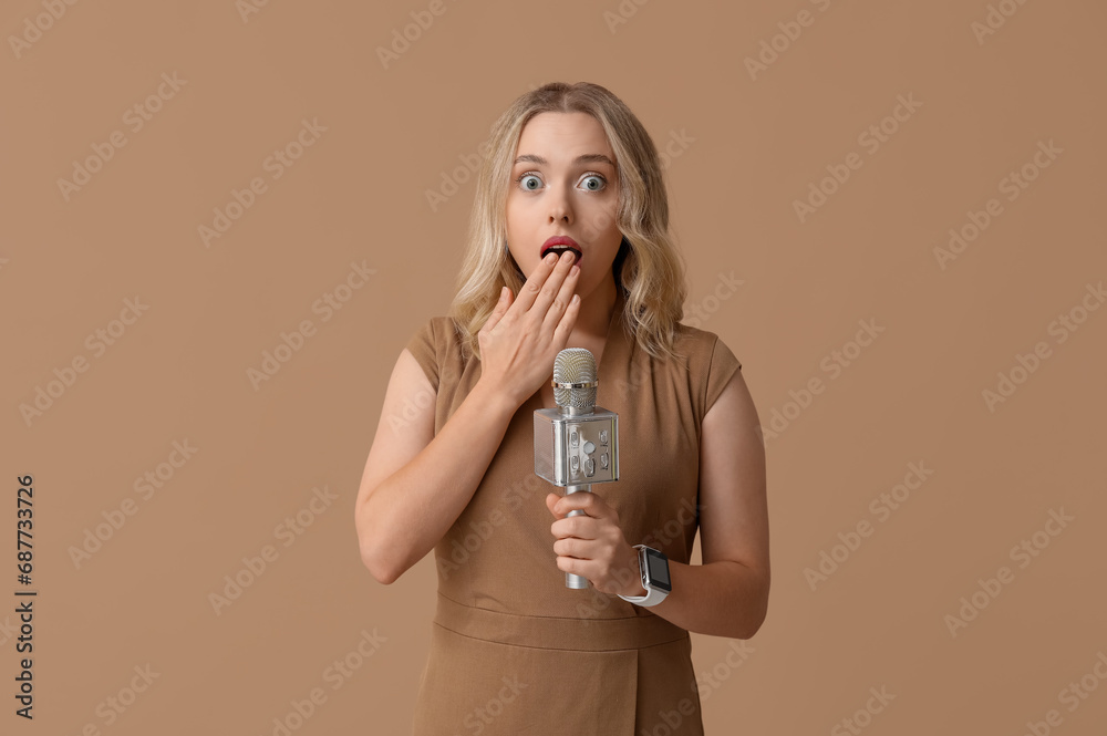 Portrait of shocked female journalist with microphone taking interview on beige background Portrait of shocked female journalist with microphone taking interview on beige background