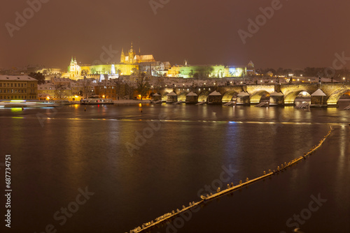 The night snowy Prague Lesser Town with gothic Castle and Charles Bridge above River Vltava  Czech Republic