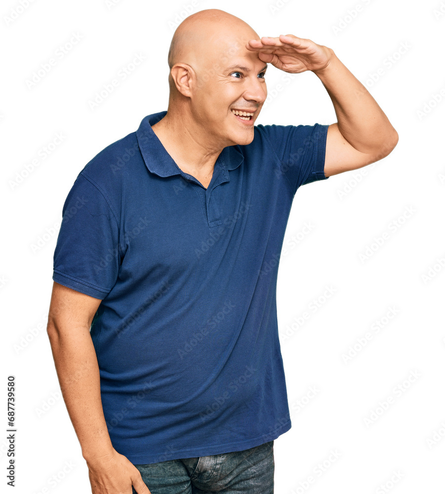 Middle age bald man wearing casual clothes very happy and smiling looking far away with hand over head. searching concept. Middle age bald man wearing casual clothes very happy and smiling looking far away with hand over head. searching concept.