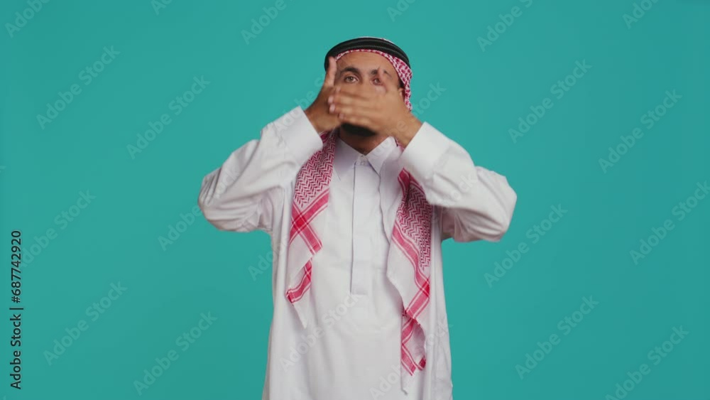 Male model covers eyes, ears and mouth on camera, presenting three wise monkeys symbol. Middle eastern person creating dont hear, see or speak metaphor sign, islamic clothing. Male model covers eyes, ears and mouth on camera, presenting three wise monkeys symbol. Middle eastern person creating dont hear, see or speak metaphor sign, islamic clothing.