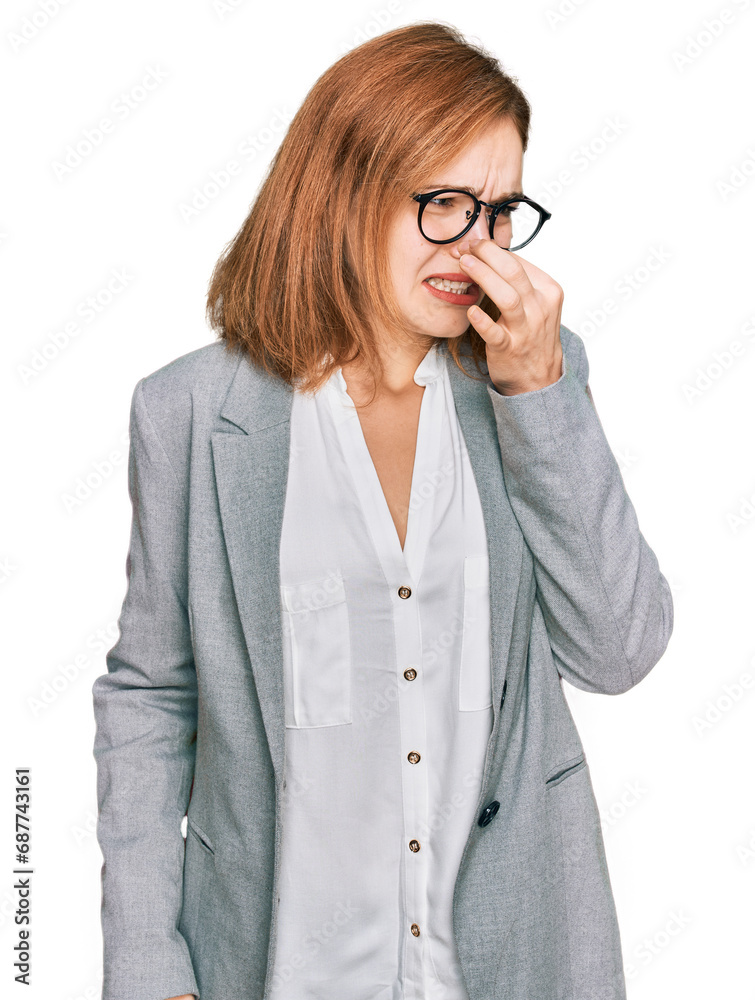 Young caucasian woman wearing business style and glasses smelling something stinky and disgusting, intolerable smell, holding breath with fingers on nose. bad smell