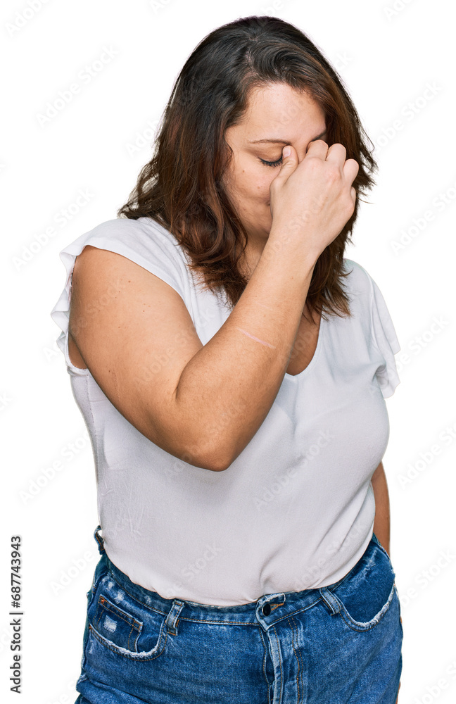 Young plus size woman wearing casual white t shirt tired rubbing nose and eyes feeling fatigue and headache. stress and frustration concept. Young plus size woman wearing casual white t shirt tired rubbing nose and eyes feeling fatigue and headache. stress and frustration concept.