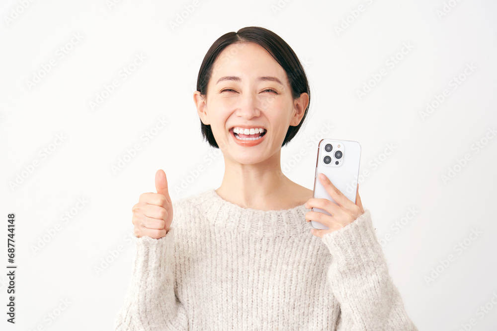 スマホを持ってグッドサインをするミドルエイジの女性 白背景 スマホを持ってグッドサインをするミドルエイジの女性 白背景