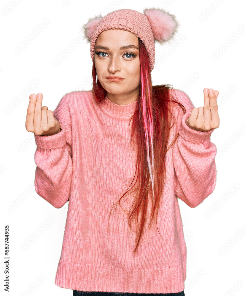 Young caucasian woman wearing casual clothes and wool cap doing money gesture with hands, asking for salary payment, millionaire business Young caucasian woman wearing casual clothes and wool cap doing money gesture with hands, asking for salary payment, millionaire business