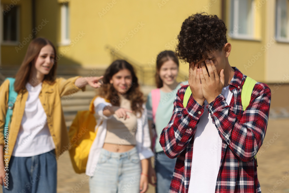 Teen problems. Group of students pointing at upset boy outdoors, selective focus