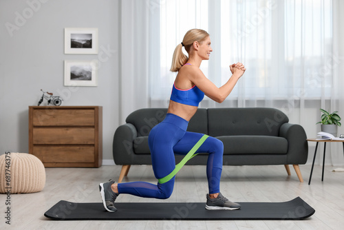 Athletic woman doing exercise with fitness elastic band on mat at home