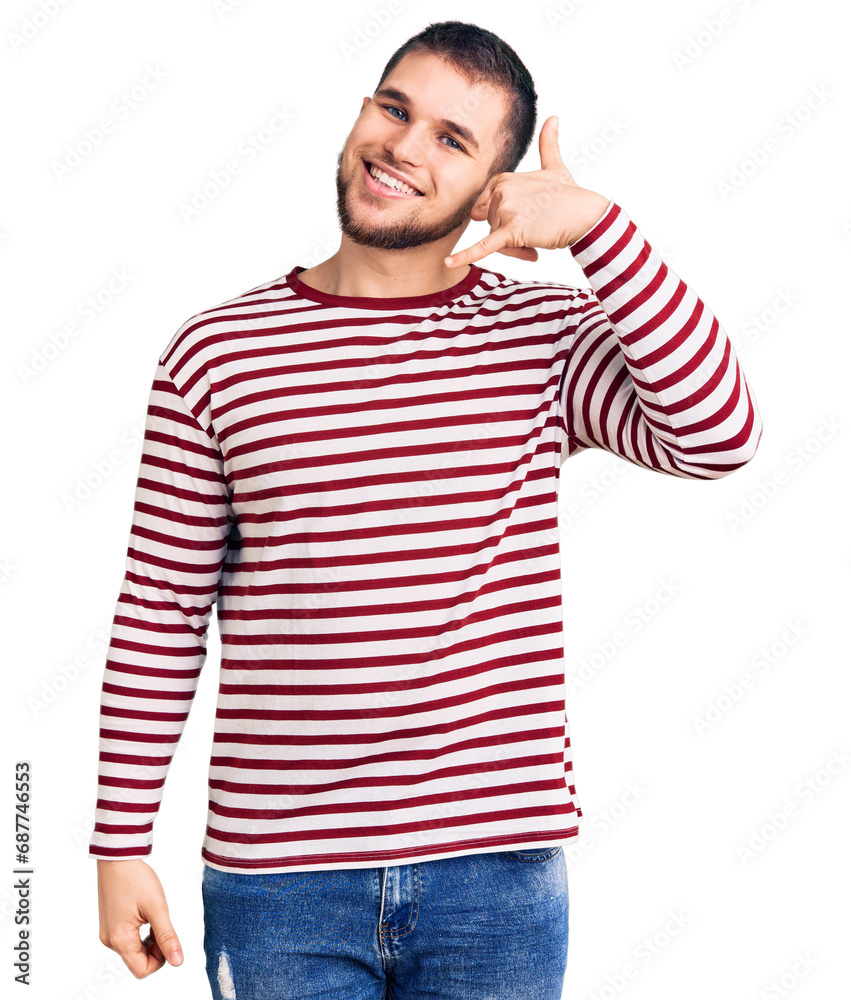 Young handsome man wearing striped sweater smiling doing phone gesture with hand and fingers like talking on the telephone. communicating concepts.