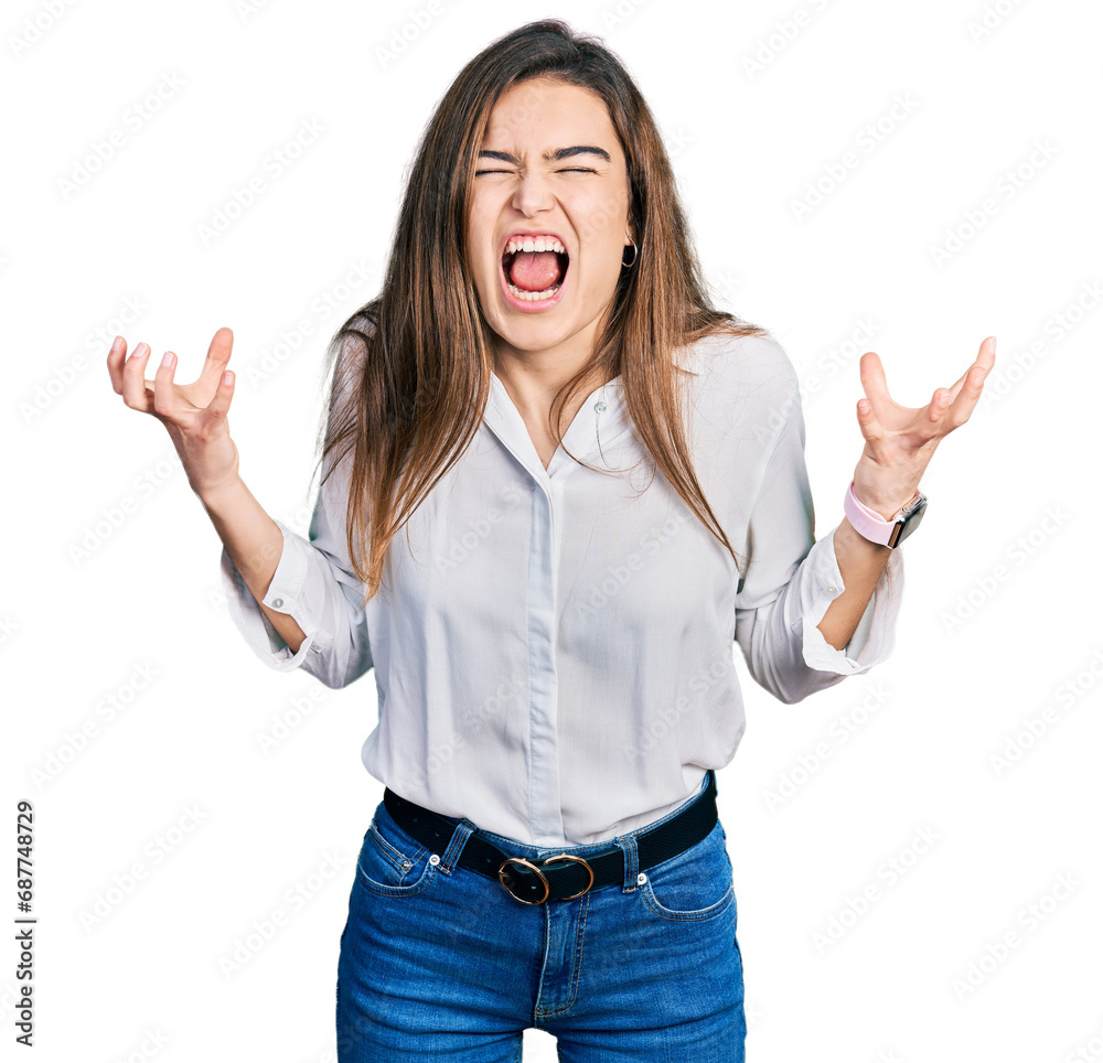 Young caucasian girl wearing casual white shirt crazy and mad shouting and yelling with aggressive expression and arms raised. frustration concept. Young caucasian girl wearing casual white shirt crazy and mad shouting and yelling with aggressive expression and arms raised. frustration concept.