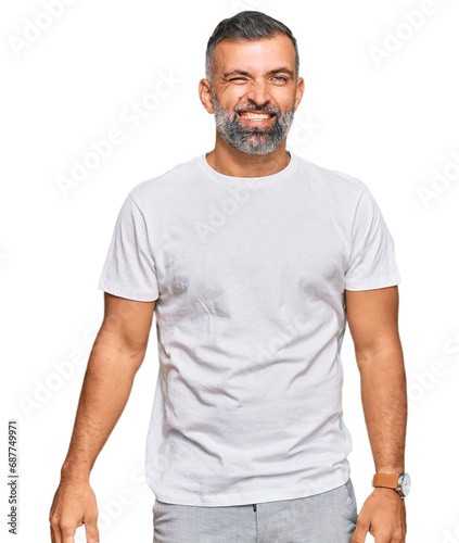 Middle age handsome man wearing casual white tshirt winking looking at the camera with sexy expression, cheerful and happy face.