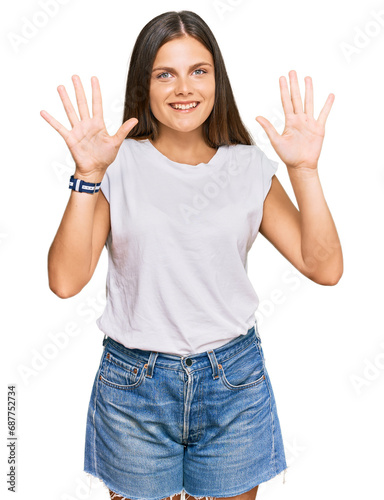Young caucasian woman wearing casual white tshirt showing and pointing up with fingers number ten while smiling confident and happy.