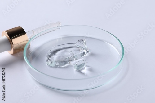 Petri dish with cosmetic serum and pipette on white background, closeup