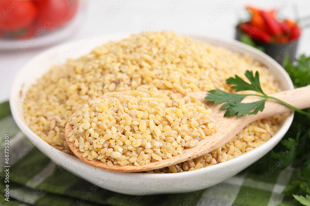 Bowl and spoon with raw bulgur on table, closeup Bowl and spoon with raw bulgur on table, closeup