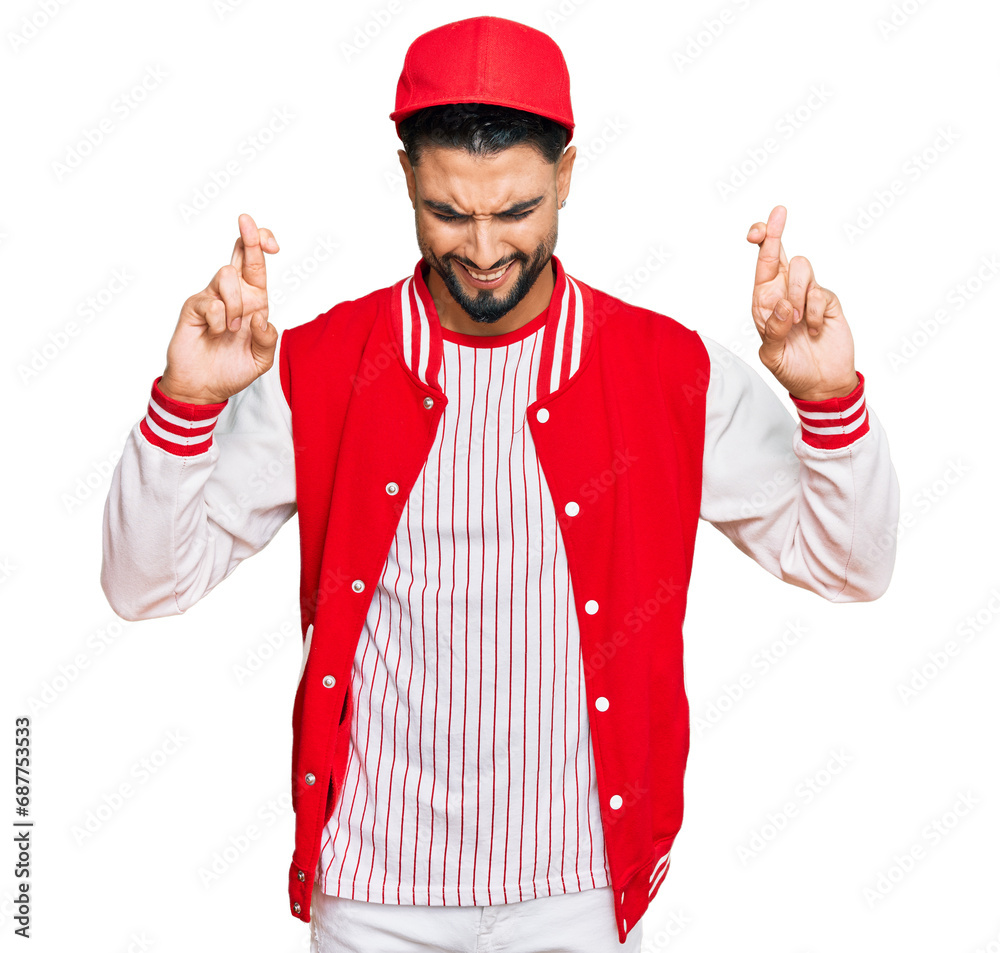 Young man with beard wearing baseball uniform gesturing finger crossed smiling with hope and eyes closed. luck and superstitious concept. Young man with beard wearing baseball uniform gesturing finger crossed smiling with hope and eyes closed. luck and superstitious concept.