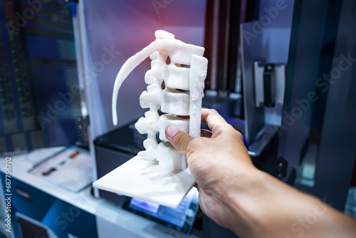 hand with 3d printed human spine in 3d printer. photo