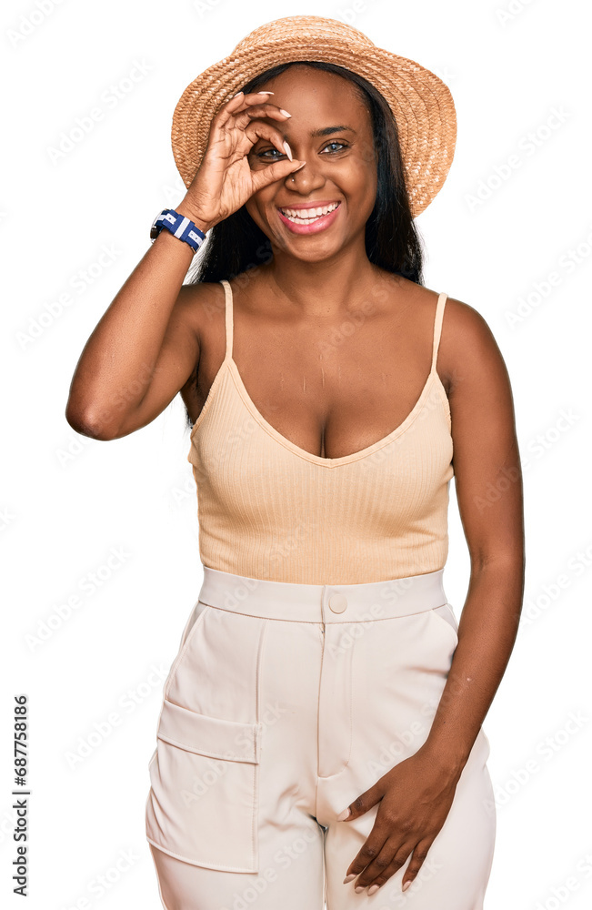 Young black woman wearing summer hat doing ok gesture with hand smiling, eye looking through fingers with happy face. Young black woman wearing summer hat doing ok gesture with hand smiling, eye looking through fingers with happy face.