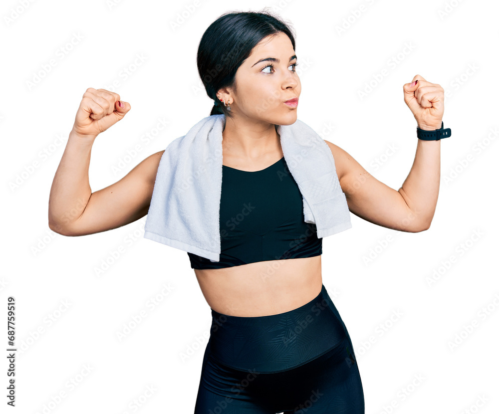 Young brunette woman with blue eyes wearing sportswear and towel showing arms muscles smiling proud. fitness concept. Young brunette woman with blue eyes wearing sportswear and towel showing arms muscles smiling proud. fitness concept.