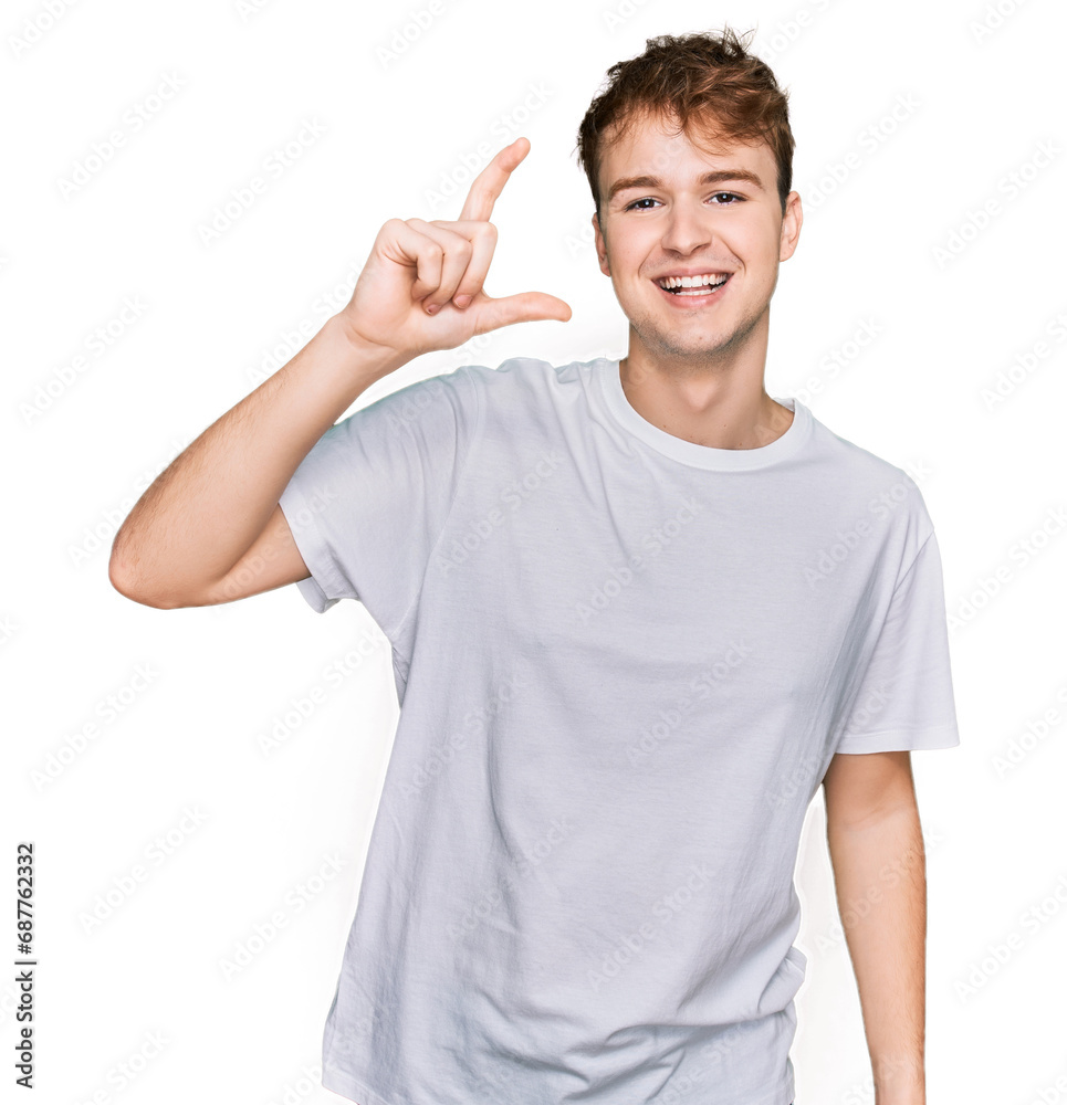 Young caucasian man wearing casual white t shirt smiling and confident gesturing with hand doing small size sign with fingers looking and the camera. measure concept. Young caucasian man wearing casual white t shirt smiling and confident gesturing with hand doing small size sign with fingers looking and the camera. measure concept.