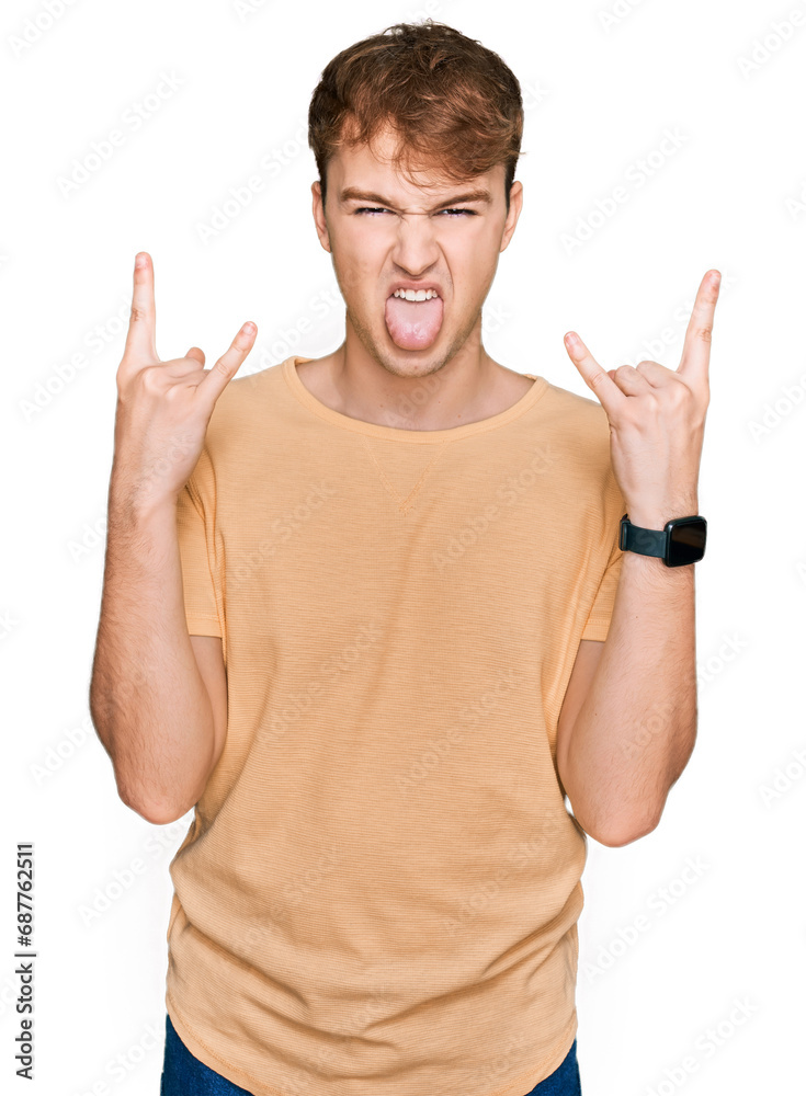 Young caucasian man wearing casual clothes shouting with crazy expression doing rock symbol with hands up. music star. heavy music concept. Young caucasian man wearing casual clothes shouting with crazy expression doing rock symbol with hands up. music star. heavy music concept.