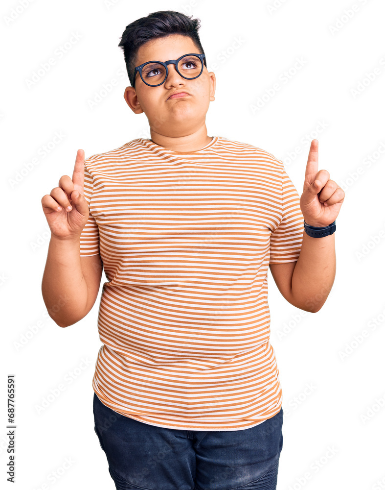 Little boy kid wearing casual clothes and glasses pointing up looking sad and upset, indicating direction with fingers, unhappy and depressed. Little boy kid wearing casual clothes and glasses pointing up looking sad and upset, indicating direction with fingers, unhappy and depressed.