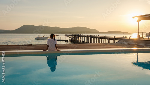 Asian woman watching sunset at a wooden pier in the ocean during sunset in Samaesan Thailand