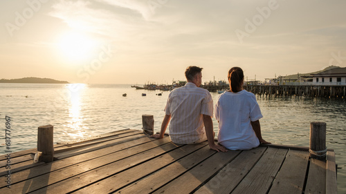 couple sitting on a wooden deck pier in the ocean during sunset in Samaesan Thailand