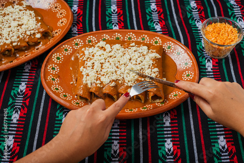 Person eating enchiladas with red pipian. Typical Mexican food. photo