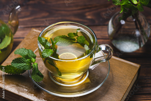 Mint tea in a teapot and cup on a wooden table