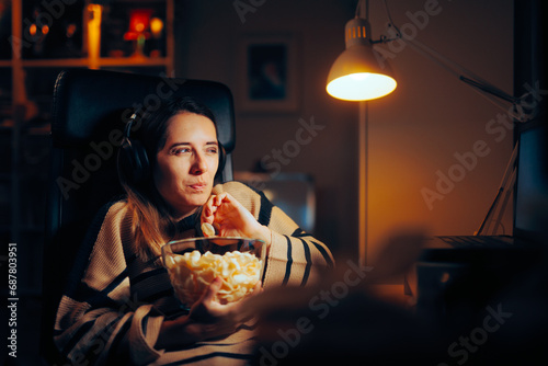 Funny Woman Eating Chips Watching a Show on her Laptop. Girl passing her leisure time at home seeing a movie 